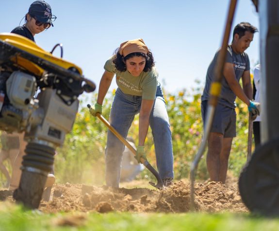 a woman uses a shovel during a Pacific volunteering event