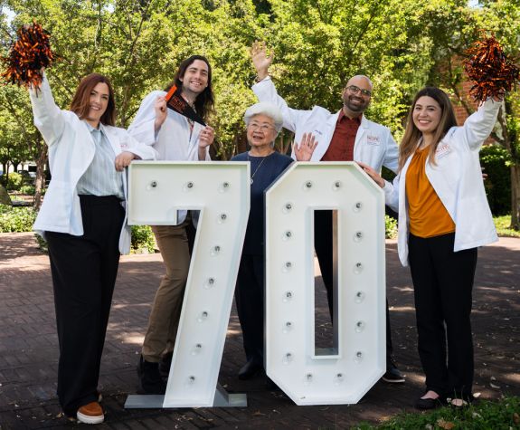 Four recent graduates with a graduate from the inaugural class