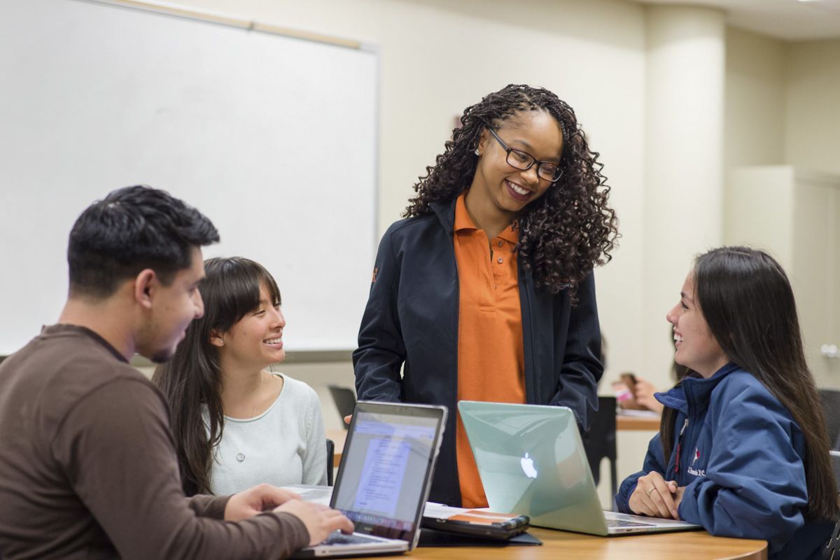 A professor with students using laptops