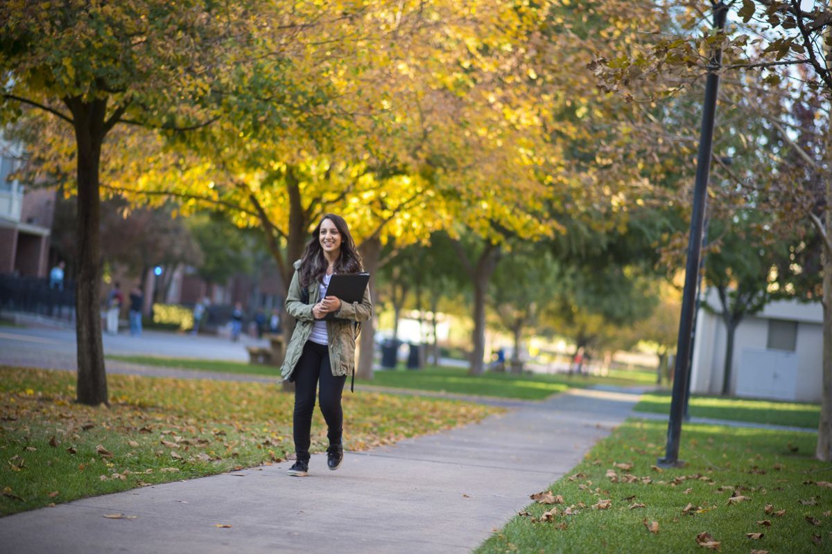 Smiling student walking on campus during fall