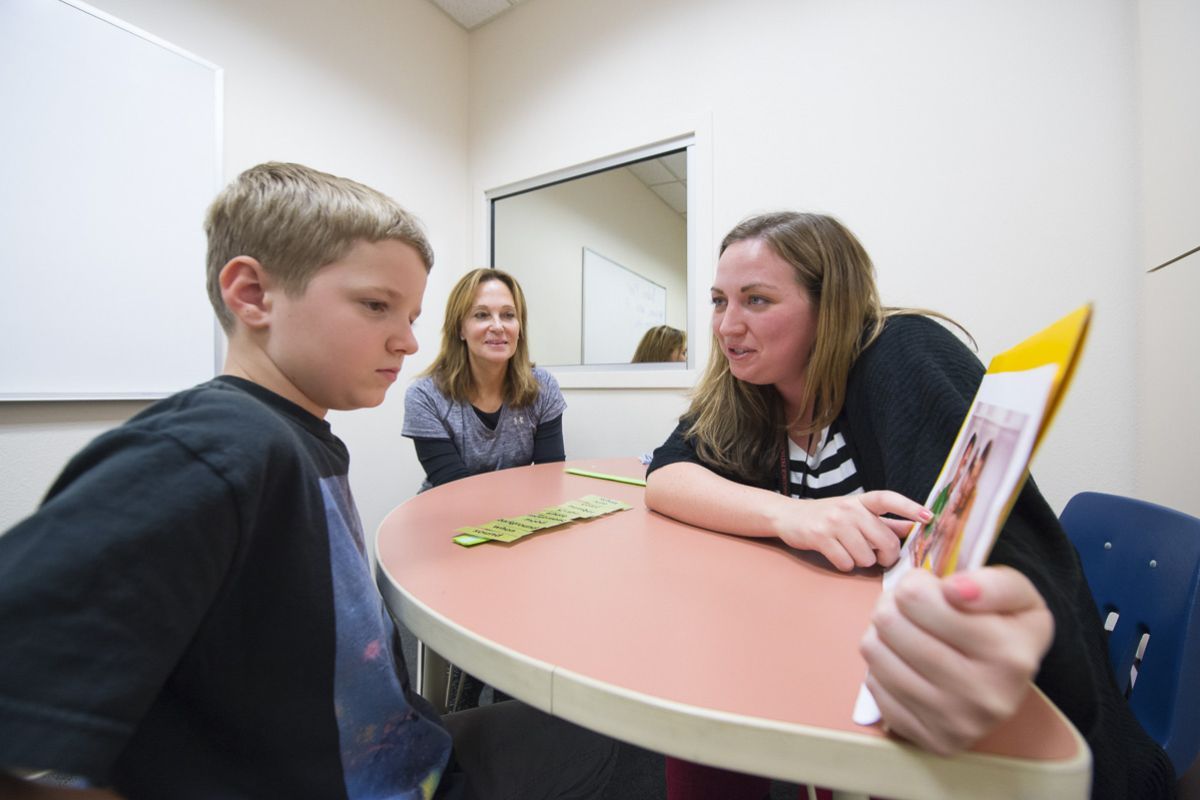 a child works with a speech-language pathologist student in a clinical setting