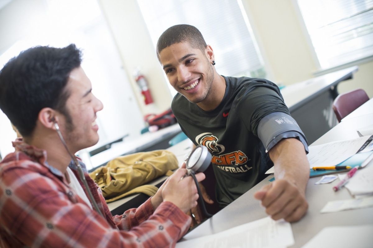 student using stethoscope on athlete