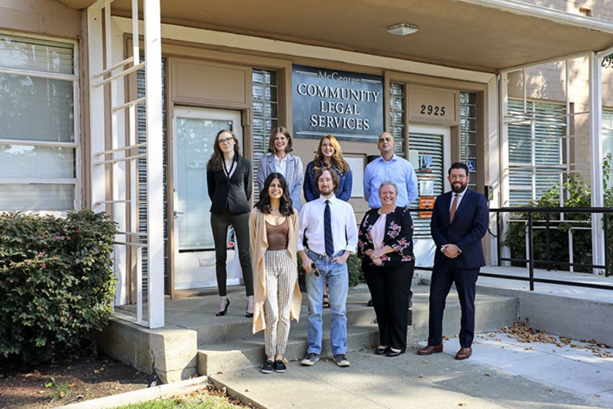 Eight people stand in front of the Community Legal Services building.