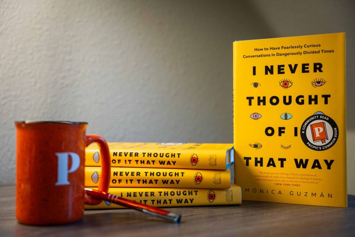 a stack of the common read books with a mug and pen
