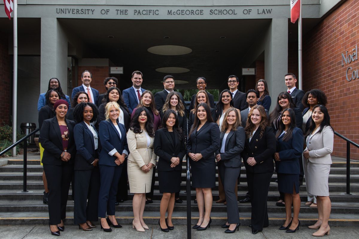 A group photo of 30 people pose for a photo outside. 