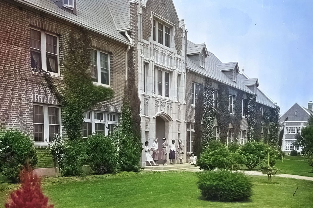 A colorized photo of Southwest Hall with some women standing by its door