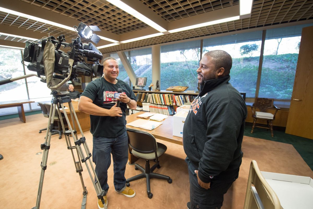 two people stand next to a video camera