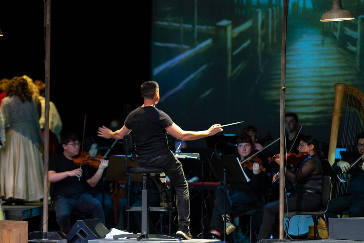 A conductor with an orchestra of a musical performance