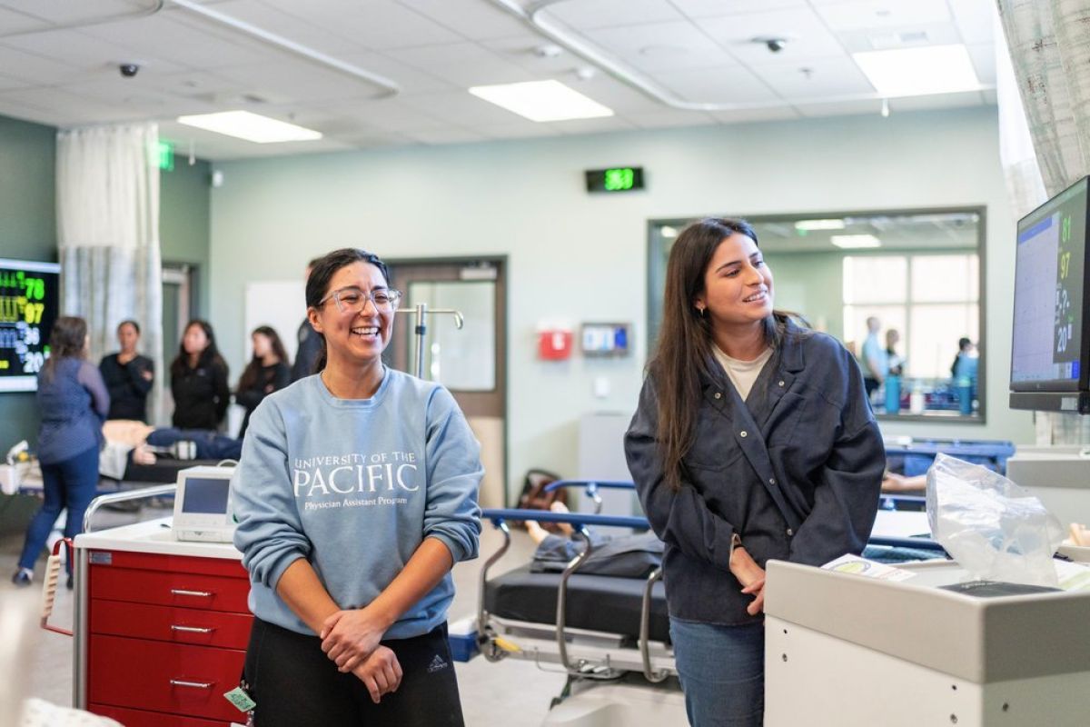 Photo shows two students standing in the lab and smiling. 