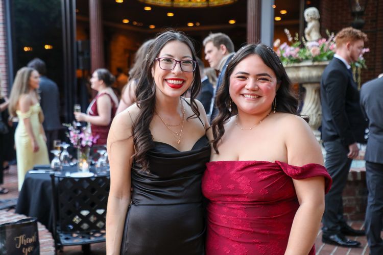 Two individuals smiling at camera dressed in fancy attire. 