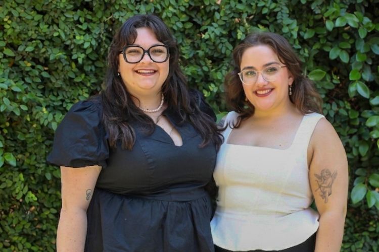 Two people stand against a green background for a professional photo. 