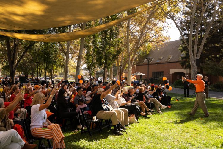 a group gathers on the lawn for a champagne toast