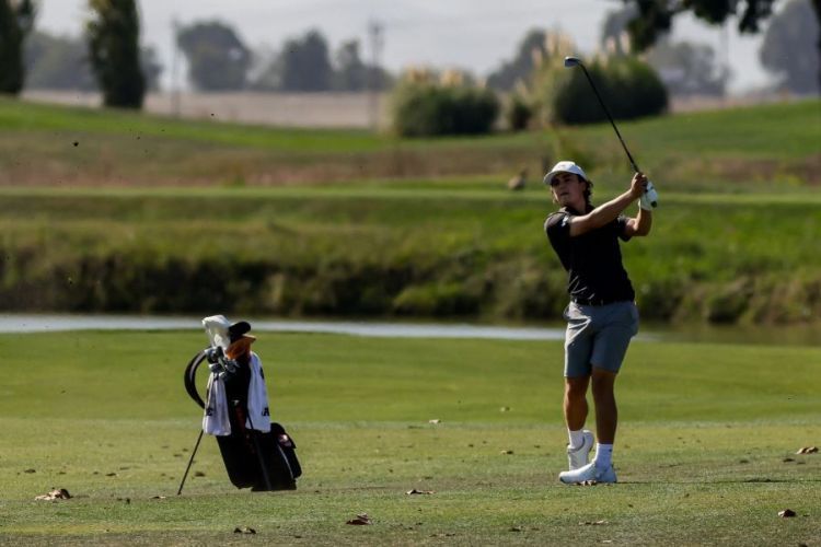 Bouchard swinging a gold club on a green course 