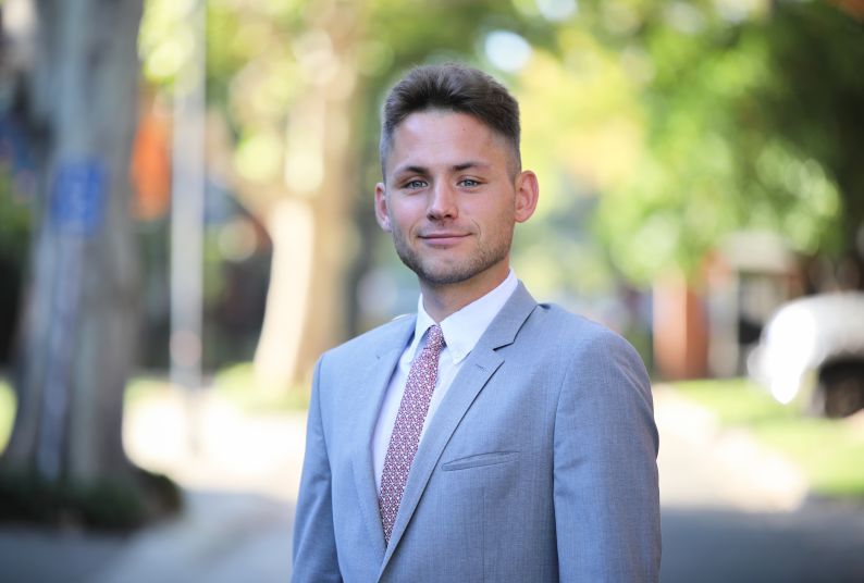 A man in a suit smiles on campus