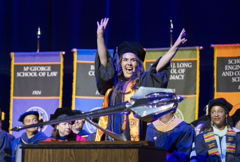 A student cheers as she walks across the stage at commencement.