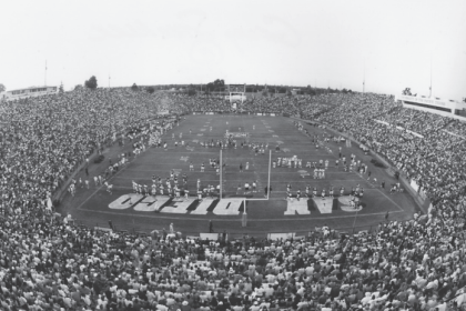 a black and white photo shows a soldout crowd watches a scrimmage at Stagg Memorial Stadium