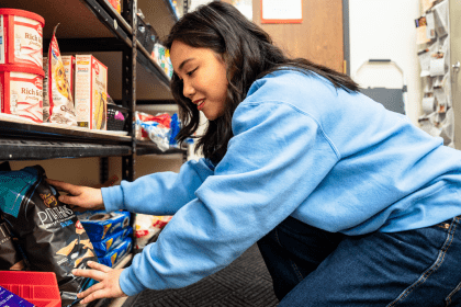 a student restocks shelves at a food pantry