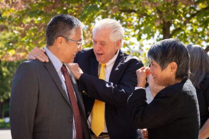 Three people embrace at DeRosa's memorial.
