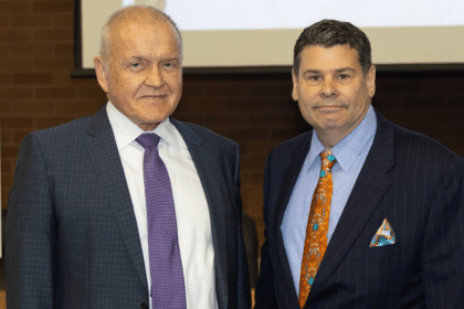 Mark Drobny and Michael T. Colatrella Jr. smile in front of a presentation.