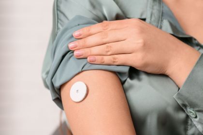 Photo of a person wearing a continuous glucose monitor on their right arm.